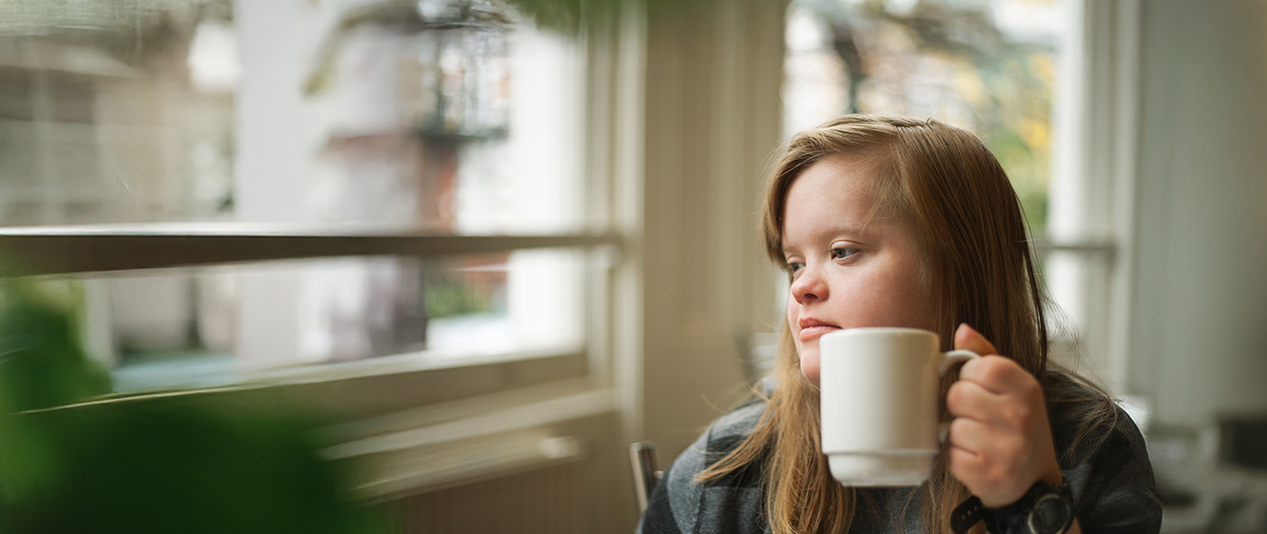 Bild zeigt eine junge Erwachsene, die vor einem Fenster sitzt.